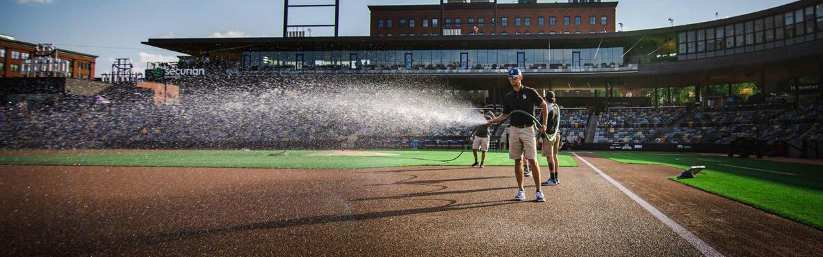 Workers working and watering a professional baseball field